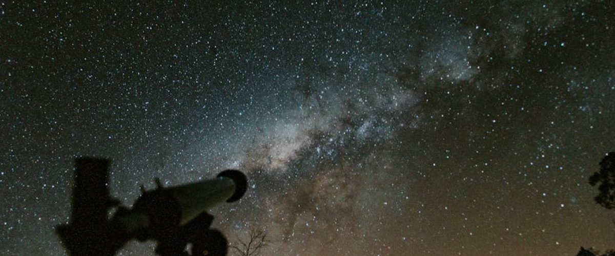 Silhouette of a telescope with a stunning Milky Way background in the night sky.